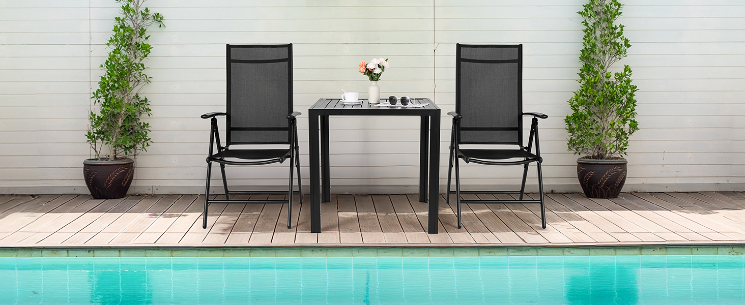 Terrasse au bord de la piscine avec deux chaises en maille noire et une petite table entre elles, flanquées de plantes en pot contre