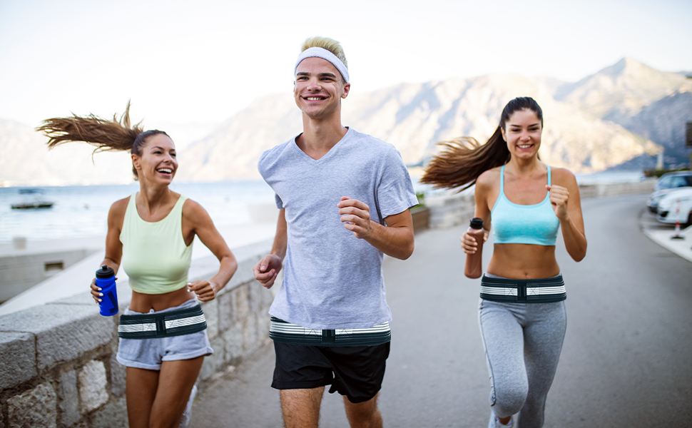 Three people jogging along a waterfront with mountains in the background. They are wearing athletic clothing and appear to be exercising together.