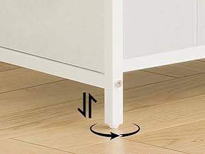 Pied de table en métal blanc avec mécanisme de nivellement réglable visible sur le plancher en bois, montrant les détails de la construction de la base du meuble.