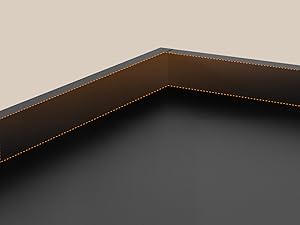 Dettaglio ravvicinato della superficie imbottita grigio scuro con cuciture decorative in oro o ottone lungo il bordo, che mostrano l'angolo o la cucitura del mobile.