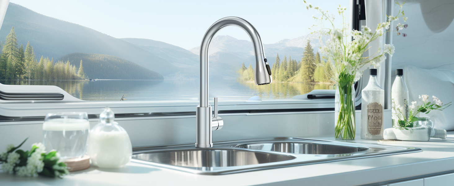 Modern kitchen sink with stainless steel faucet. Scenic lake view through window. White countertop with soap dispensers and flower vase.