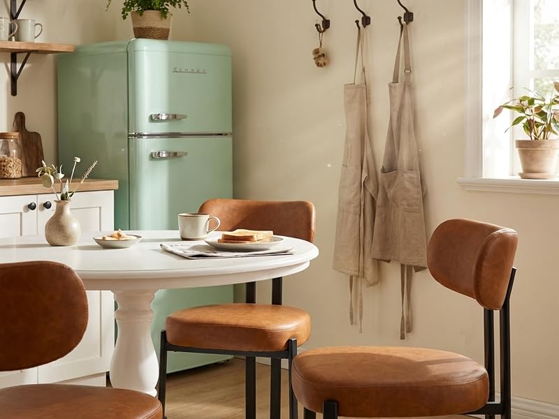 Salle à manger intérieure avec réfrigérateur vert menthe et chaises en cuir marron autour d'une table blanche. Plusieurs angles de configuration moderne de la cuisine-salle à manger.