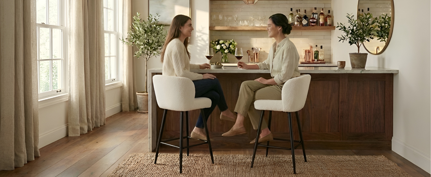 Modernes Kücheninterieur mit zwei weißen Barhockern an der Holztheke, Tageslicht und dekorativen Pflanzen.