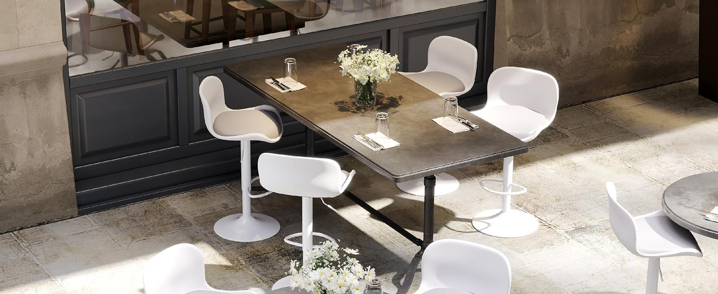 Modern restaurant or cafe interior featuring long communal tables with white chairs. Space has industrial-style lighting and minimalist decor.