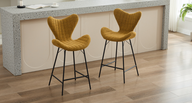 Diseño interior moderno con sillas tapizadas de color amarillo mostaza con patas de metal negro contra paredes blancas y pisos claros.