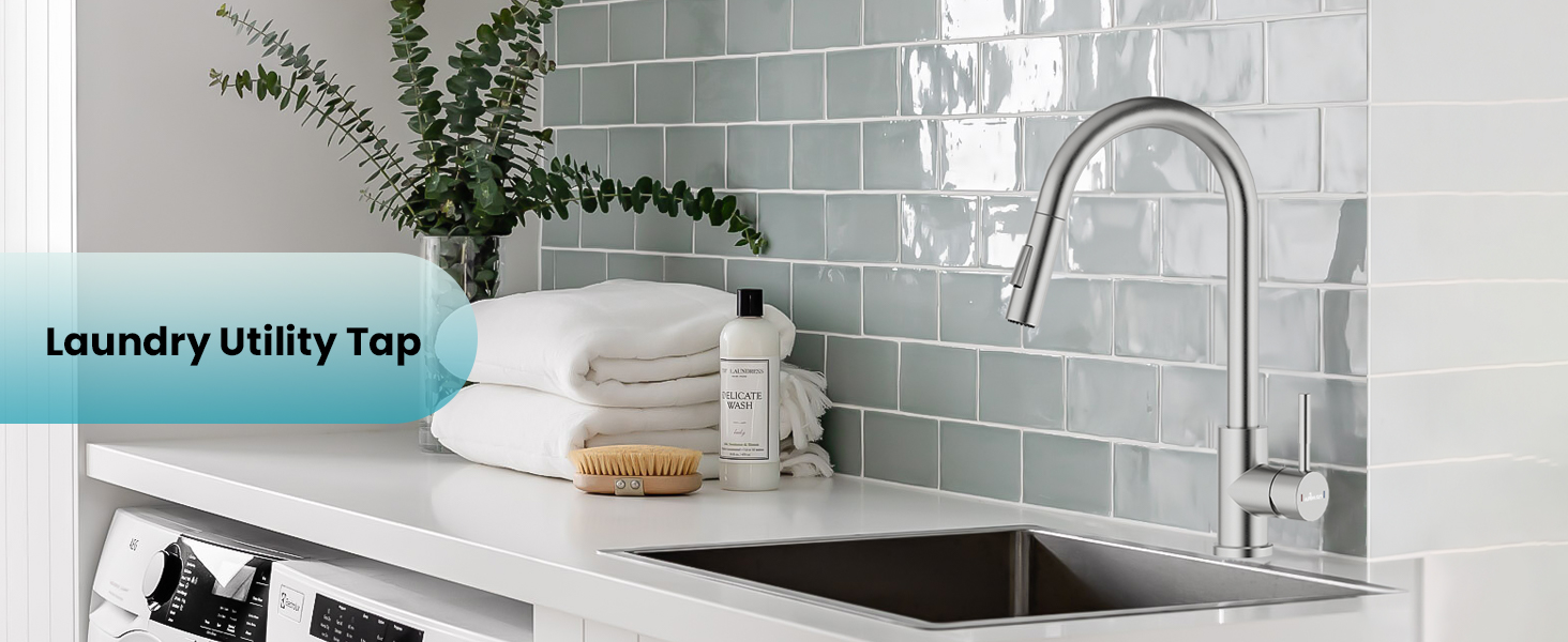 Laundry utility tap with curved spout over stainless steel sink. White countertop, green tiled backsplash, folded towels, and laundry accessories visible in modern laundry room setting.