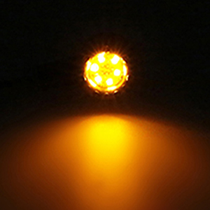 Circular LED light emitting bright yellow-orange illumination against a dark background, casting a warm glow below.