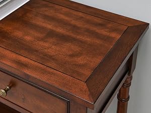 Nahaufnahme eines hölzernen Beistelltisches mit einer satten braunen Oberfläche. Verfügt über eine einzelne Schublade und gedrehte Beine, die traditionelle Handwerkskunst zur Schau stellen