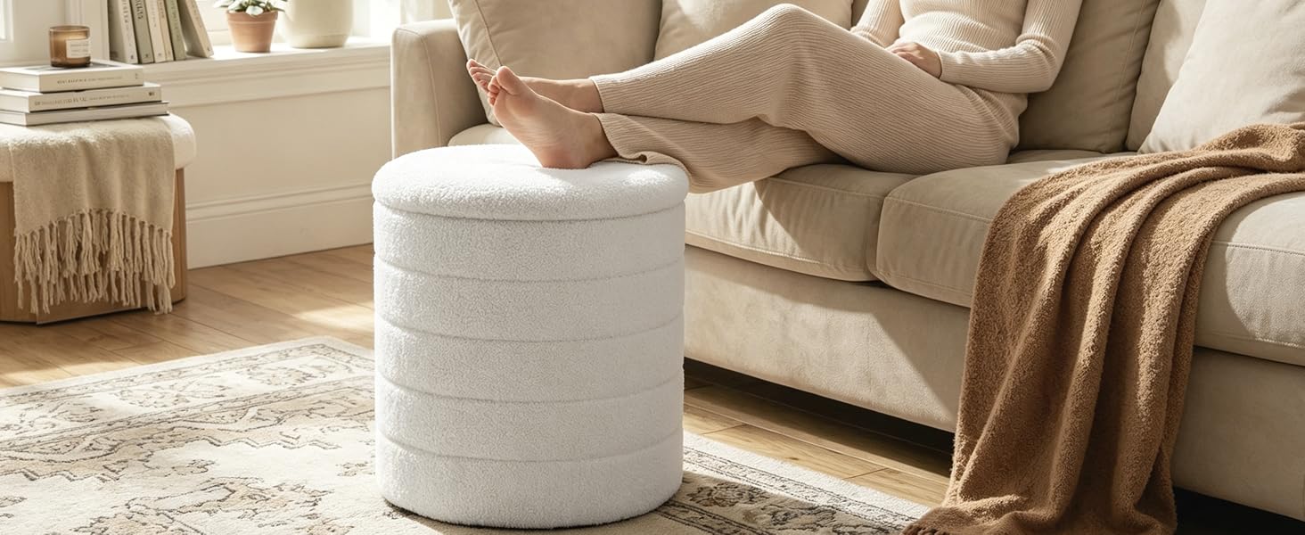 Weißer zylindrischer Aufbewahrungsbehälter oder Sitzpuff aus Stoff auf hellem Holzboden neben beigen Polstermöbeln mit Bettdecke.