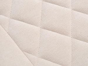 Gros plan d'un tissu matelassé blanc ou d'une surface de matelas présentant des coutures à motif en losange et une texture rembourrée.