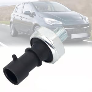 Automotive sensor with black plastic body and metal hex nut. Cylindrical shape with protruding electrical connector. Background shows a gray hatchback car on a road.