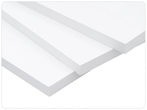 Tres tablas o paneles gruesos y rectangulares de espuma blanca apilados uno encima del otro, que muestran su grosor uniforme y su superficie lisa