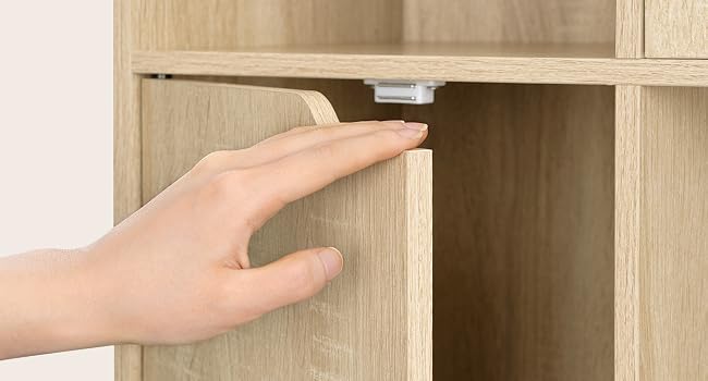 Primer plano de la mano que se extiende hacia un armario de madera o un cajón para muebles con un acabado minimalista de madera clara, que demuestra el acceso a cajones o compartimentos de almacenamiento.