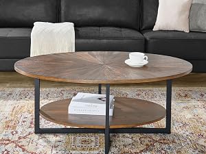 Runder industrieller Couchtisch mit Holzplatte, Metallrahmen und unterer Ablage, der vor einem schwarzen Ledersofa steht.