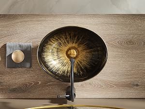 Lavabo de vaso moderno con superficie interior metálica negro‑dorada texturizada, instalado sobre superficie de madera con grifo de pared.