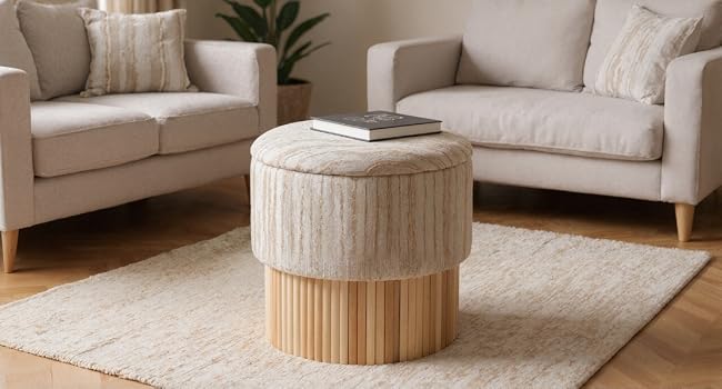 L'intérieur du salon moderne comprend un canapé sectionnel gris clair, une table basse cylindrique beige et un décor minimaliste sur des murs neutres.