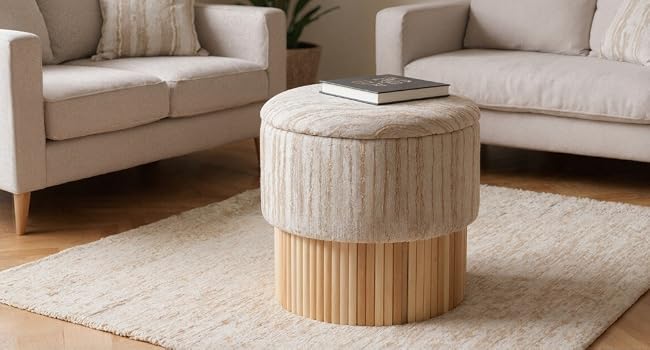 Modernes Wohnzimmerinterieur mit einem hellgrauen Ecksofa, einem beigen zylindrischen Couchtisch und minimalistischem Dekor vor neutralen Wänden.