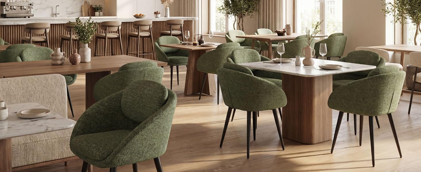 L'intérieur de la salle à manger moderne comprend des chaises rembourrées vertes avec des pieds en métal autour d'une table en bois, un éclairage chaleureux et une décoration neutre.