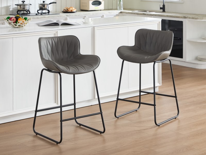 Modern gray upholstered counter stools with black metal sled bases arranged along white kitchen counter, showing contemporary dining setup.