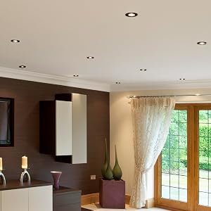 Innenraumansichten mit Deckeneinbauleuchten, die in einem modernen Wohnraum mit Fenstern und warmer Beleuchtung installiert sind.