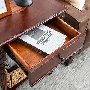 Beistelltisch aus Holz mit offener Schublade, auf der ein Buch zum Vorschein kommt. Er verfügt über gedrehte Beine, eine untere Ablage mit Korb und einen teilweise sichtbaren Ledersessel.