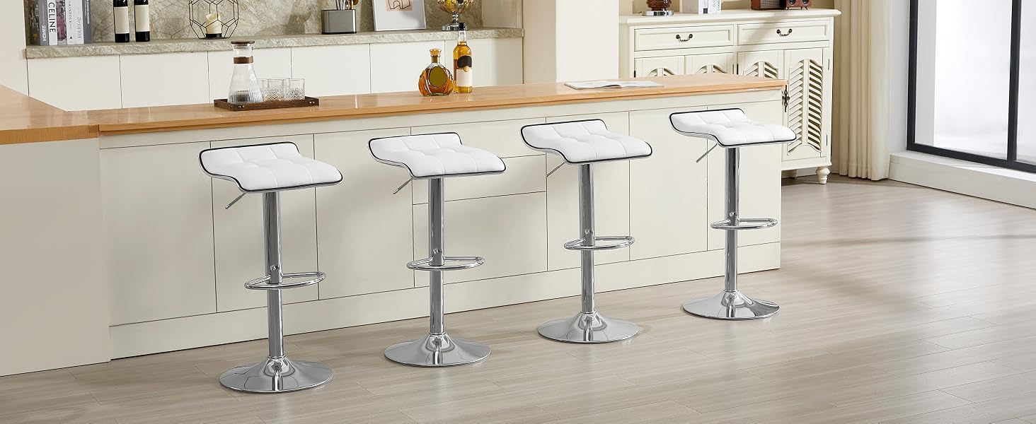Quattro moderni sgabelli da bar regolabili con basi cromate e sedili bianchi. Posizionati su un'isola da cucina in legno in uno spazio luminoso e aperto.