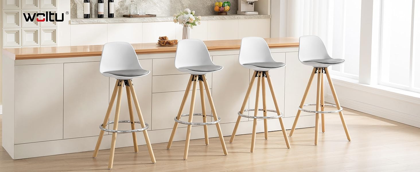 Cuatro taburetes de bar modernos con asientos de plástico blanco y patas de trípode de madera, dispuestos en fila en la encimera de la cocina. Los taburetes presentan un diseño minimalista