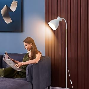 Frau mit Tablet auf der Couch neben weißer Stehlampe. Das Zimmer verfügt über eine blaue Wand, einen roten Vorhang und dekorative schwebende Papierelemente.