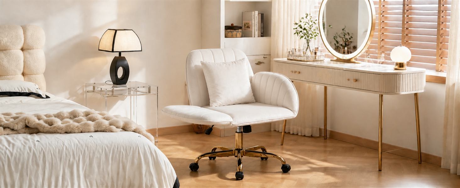 Interno della camera da letto con letto imbottito beige, poltrona color crema con ruote su pavimento in legno, scrivania con specchio, lampada da tavolo e arredamento caldo e neutro.