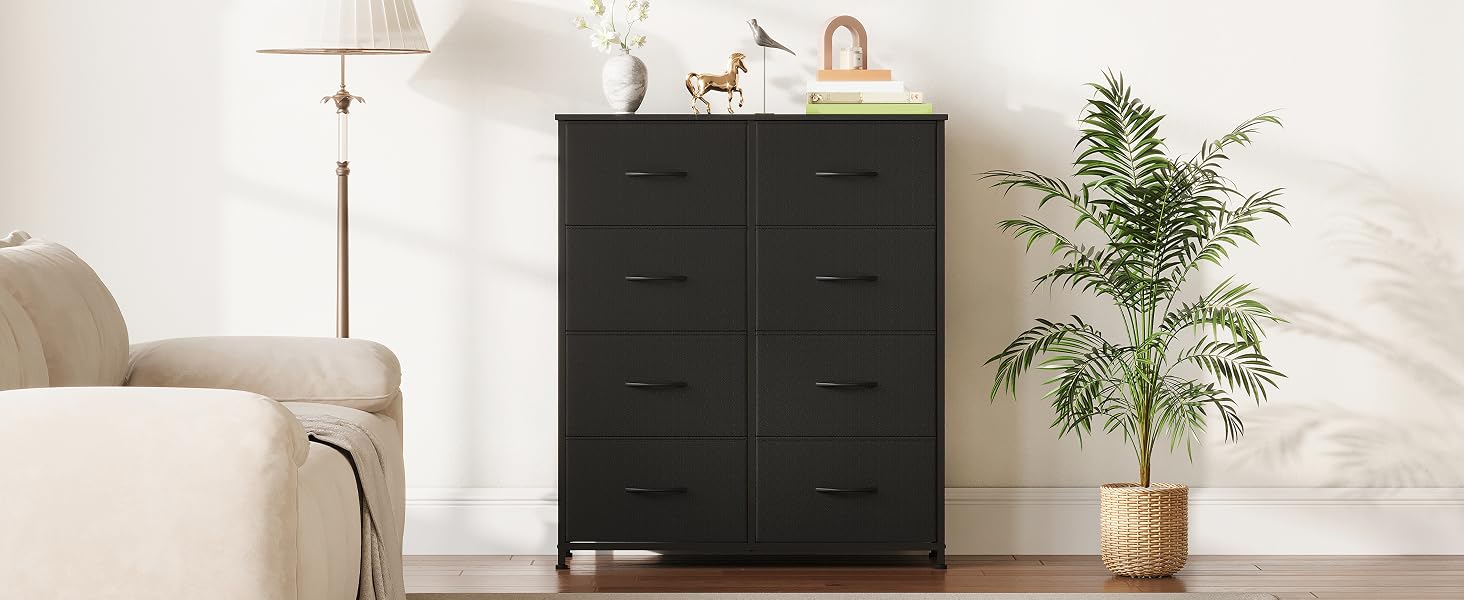 Commode gris foncé à six tiroirs avec structure et pieds en métal. Placé contre un mur blanc, entouré de plantes en pot et offrant une vue partielle de la lampe et du fauteuil