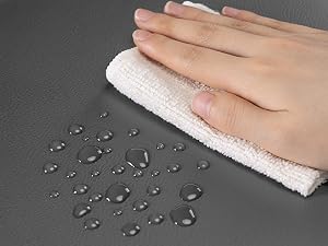 Dimostrazione di una superficie resistente all'acqua che mostra gocce d'acqua che si depositano su una superficie grigio scuro, con gocce che si puliscono a mano con un panno.