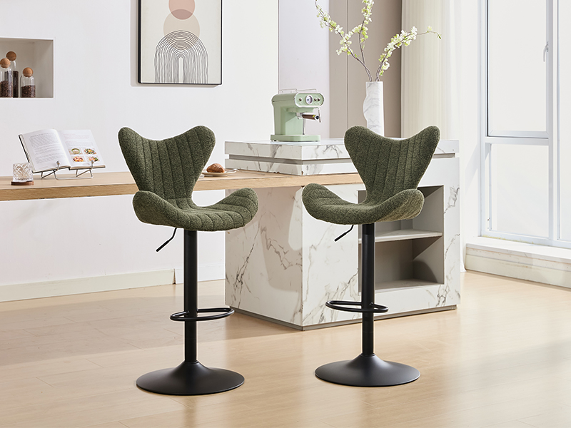 Two olive green velvet upholstered swivel bar stools with curved wing-back design and black metal pedestal bases in modern interior setting.