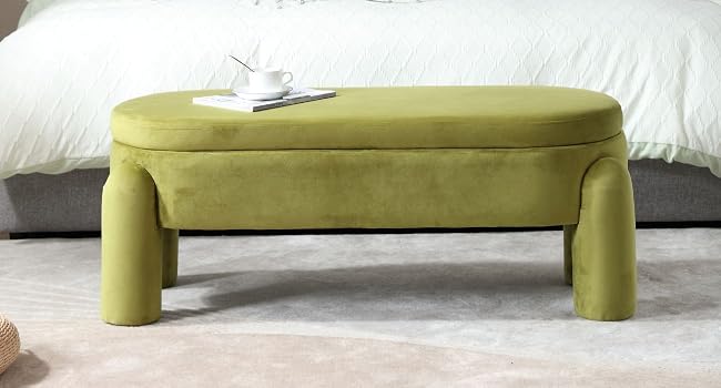 Banco u otomano moderno tapizado en verde oliva con distintivas patas curvas, colocado contra ropa de cama blanca.
