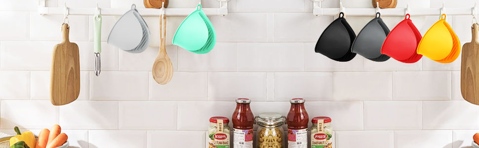 Los mangos de silicona coloré de diferentes formas crochés es un mur carrelé blanc au-dessus de planches à couper en bois et de bocaux en verre.