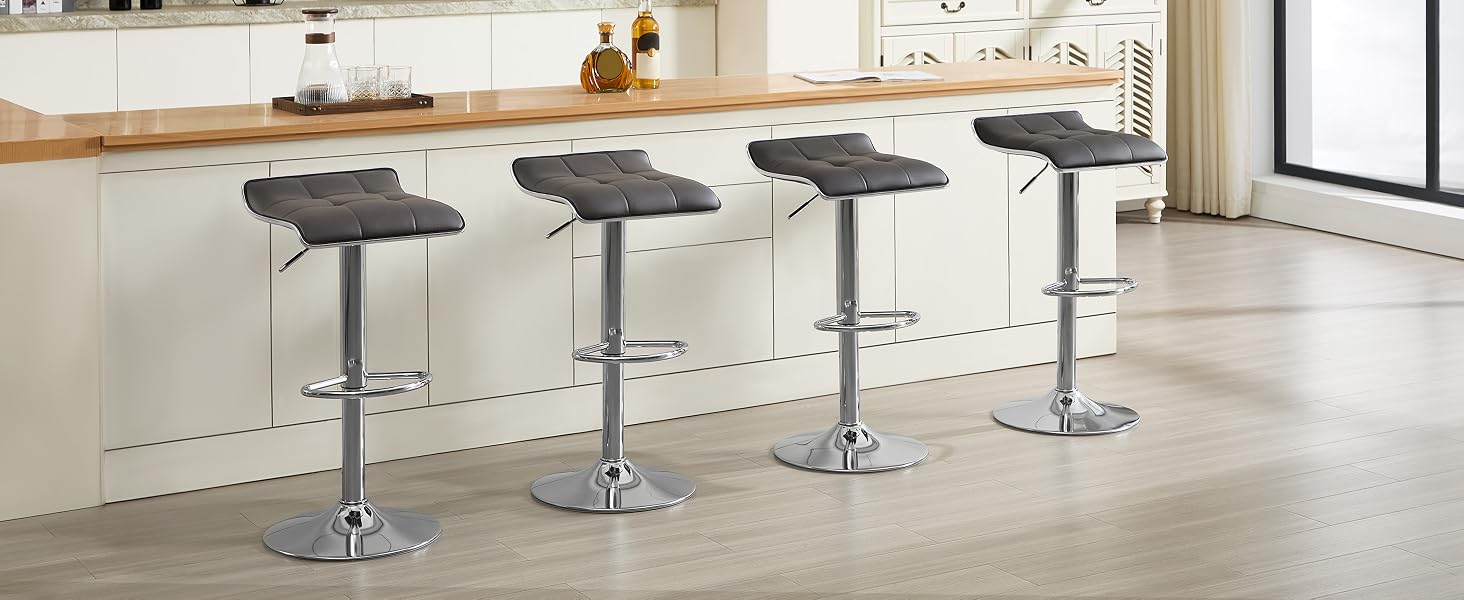 Quattro sgabelli da bar regolabili con sedili imbottiti grigi e basi cromate, allineati al bancone della cucina. Gli sgabelli presentano un design curvo del sedile e meccanismi di sollevamento idraulici