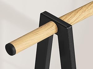 Foto ravvicinate di tasselli o aste di legno posizionati tra staffe di montaggio nere o supporti contro una superficie bianca.
