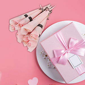 Pink-themed gift arrangement featuring roses, a wrapped present with bow, and a white plate on a pink background with heart decorations.