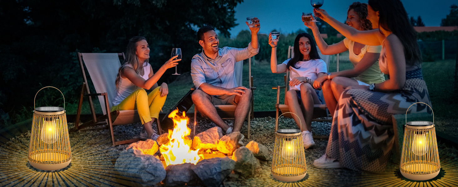 avec couvercles tissés de style bambou entourant un feu de camp. Les personnes assises sur des chaises font griller des boissons tout en profitant de la lumière chaude en soirée.