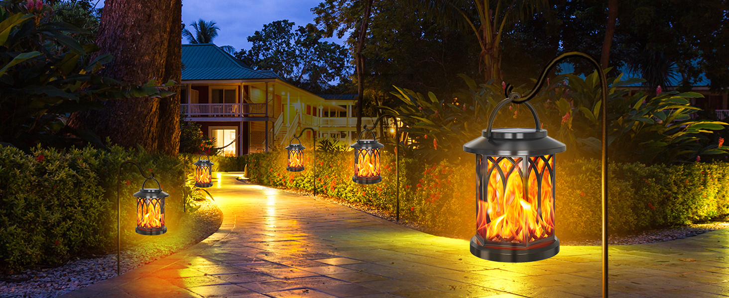 Illuminated decorative lanterns along garden pathway at night, featuring warm lighting and intricate pattern designs casting shadows.
