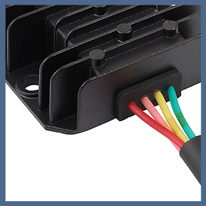 Close-up of an electronic device with a black heat sink and multiple colored wires (red, yellow, blue, green) emerging from a connection port.