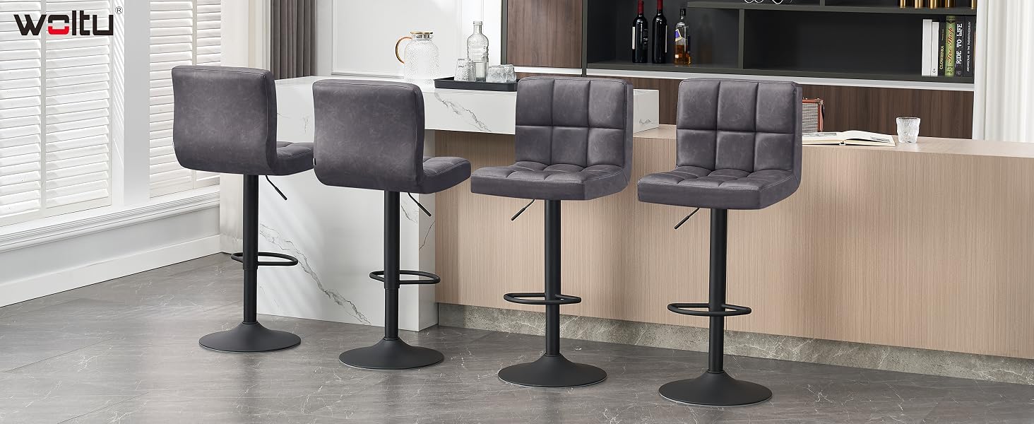 Cuatro taburetes de bar ajustables de terciopelo gris con respaldos capitonados y bases de metal negro, colocados en una isla de cocina en un ambiente interior moderno