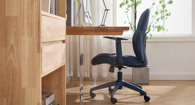 Modern home office setup with wooden desk against white wall, featuring ergonomic blue office chair and natural lighting from window. Clean, minimalist workspace design.