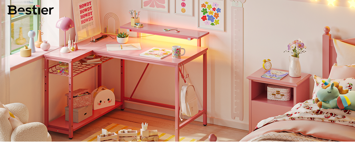 Le texte indique 'Bestier'. Bureau en métal rose avec bande lumineuse LED intégrée, représenté dans une chambre d'enfant avec des éléments de décoration roses et des peluches.