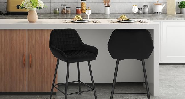 Modern kitchen interior featuring minimalist design with white tile backsplash, pendant lights, wooden cabinets, and black dining chairs against concrete flooring.