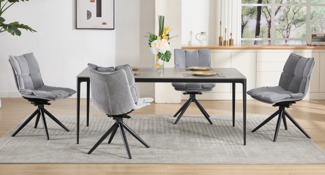 Modern dining set featuring grey upholstered chairs with swivel bases around rectangular black table. Minimalist room setting with hardwood floors and area rug.