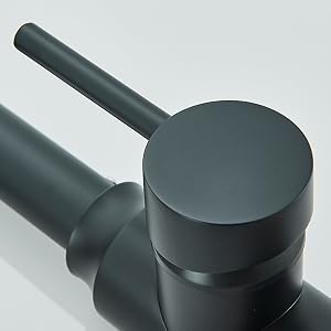 Primer plano de la manija de un grifo negro mate con un cuerpo cilíndrico y una parte superior circular, que muestra su diseño minimalista