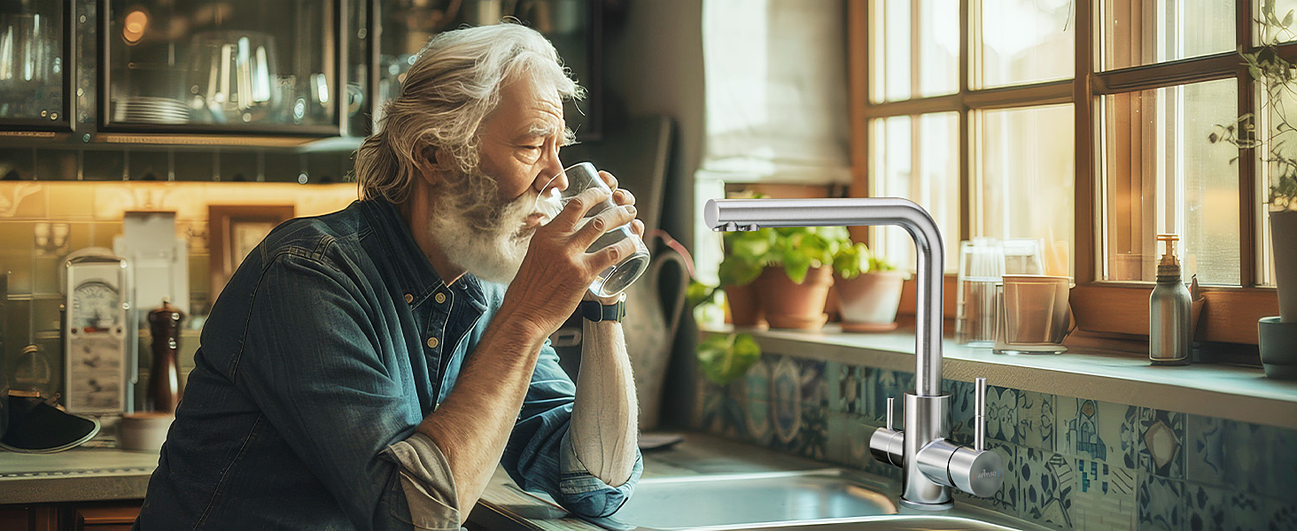 A person enjoying a beverage while sitting near a window in a rustic kitchen setting with potted plants visible in the background.
