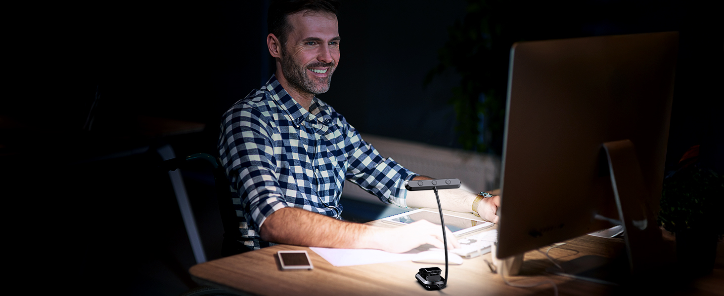 Configuration de l'espace de travail de bureau avec écran d'ordinateur et petite lampe de bureau dans un environnement sombre.