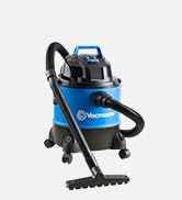 Aspiratore umido/secco blu e nero con ruote larghe e serbatoio cilindrico. Dispone di un tubo lungo e di diversi accessori per varie attività