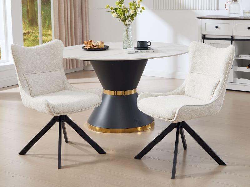 Modern dining set featuring a round black pedestal table with gold accent band, surrounded by white upholstered chairs with black metal spider legs.